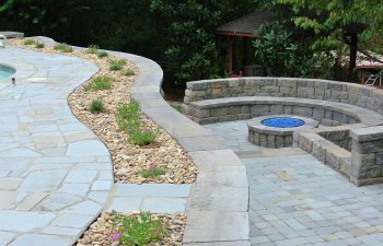 Stone patio with a fireplace and a forest in the background