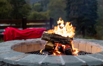 outdoor fireplace with a bright yellow flame in a fire pit and autumn forest background